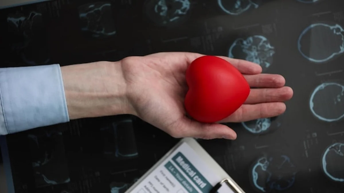 Czerwone serce w dłoni na tle karty medycznej