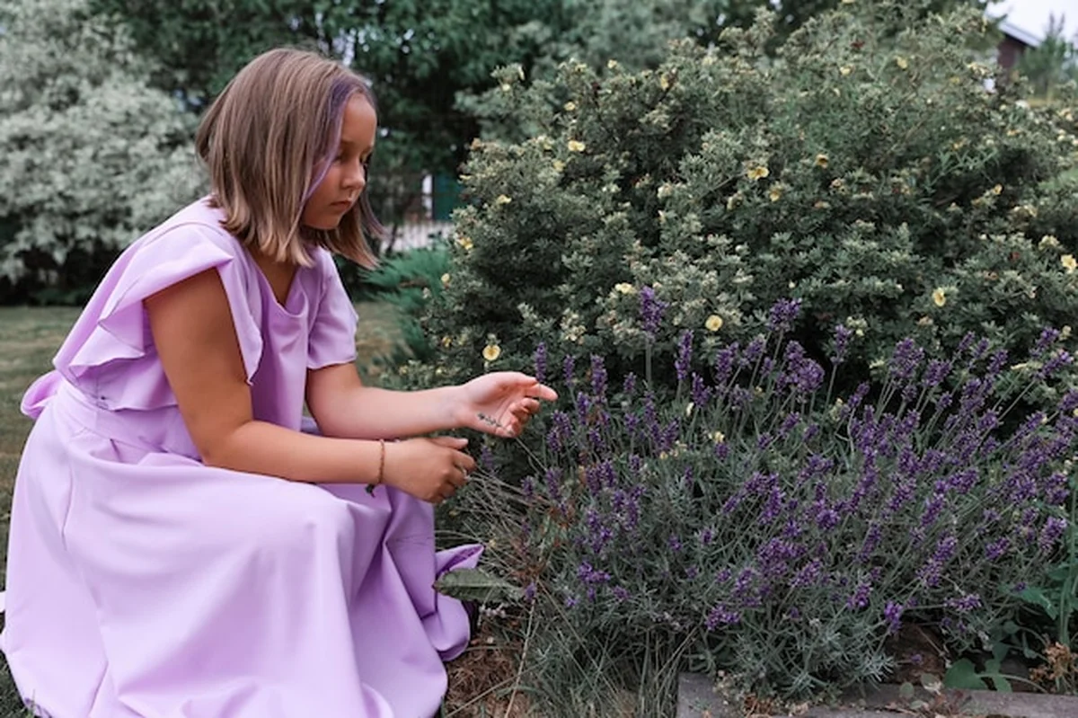 Dziewczyna w sukience przy lawendowym krzaku w ogrodzie w upalny letni dzień