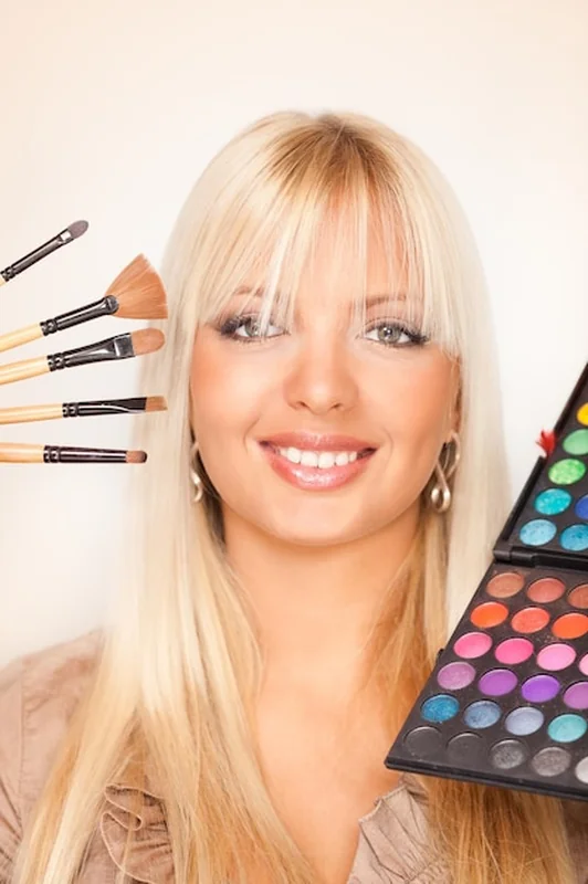 Młoda kobieta trzymająca cienie do powiek i pędzle do makijażu