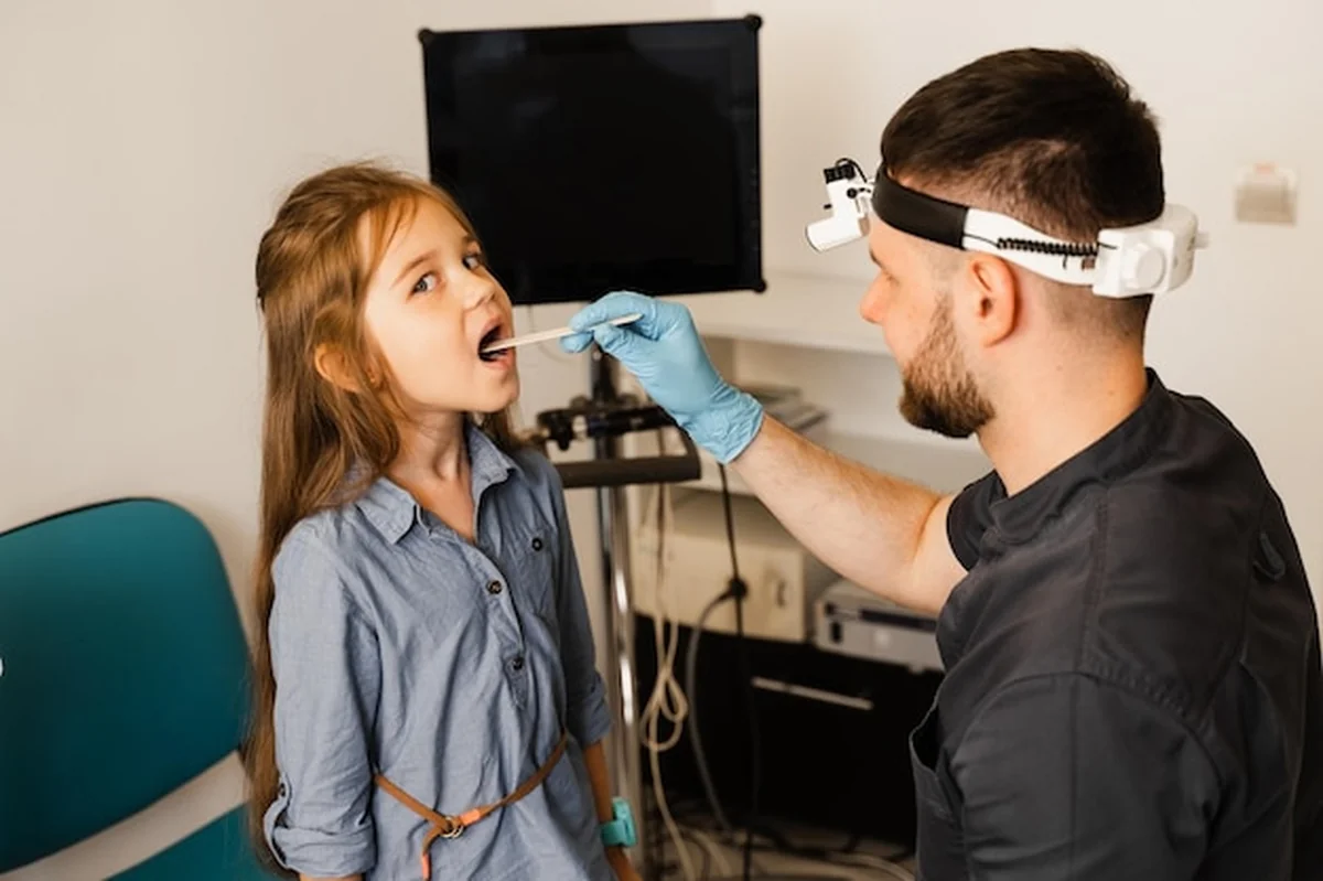 Otolaryngolog bada gardło dziecka szpatułką
