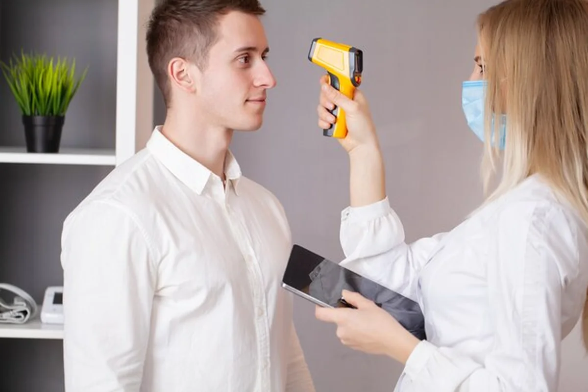 Lekarz mierzy temperaturę pacjenta termometrem laserowym