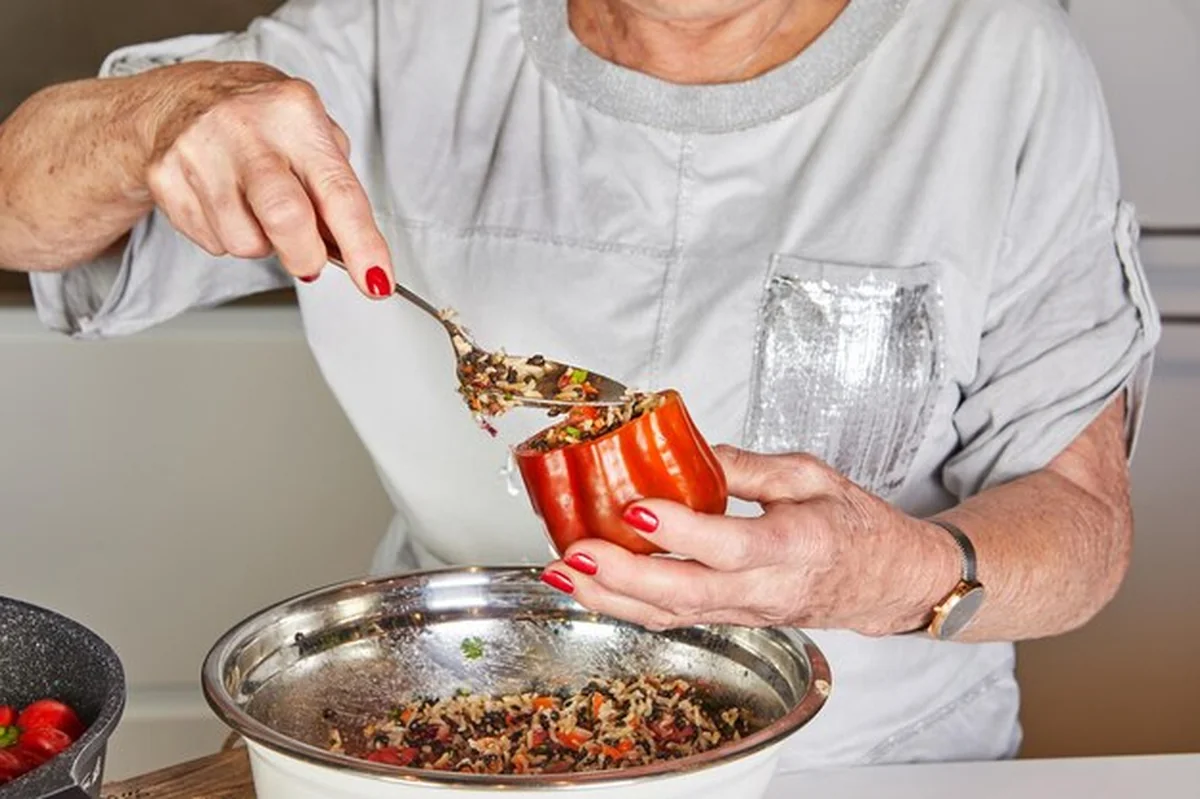 Kobieta napełnia czerwoną paprykę w kuchni