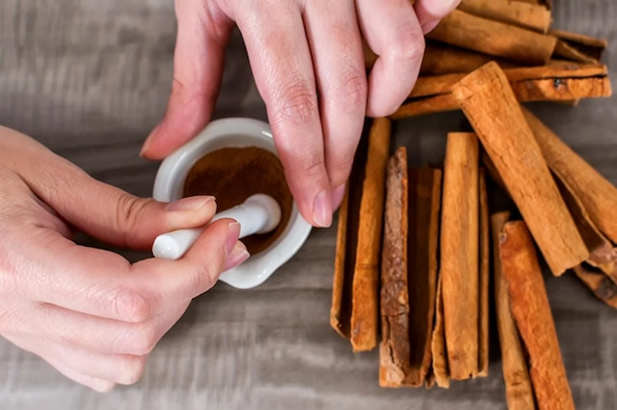 Osoba mieląca cynamon w moździerzu i tłuczku