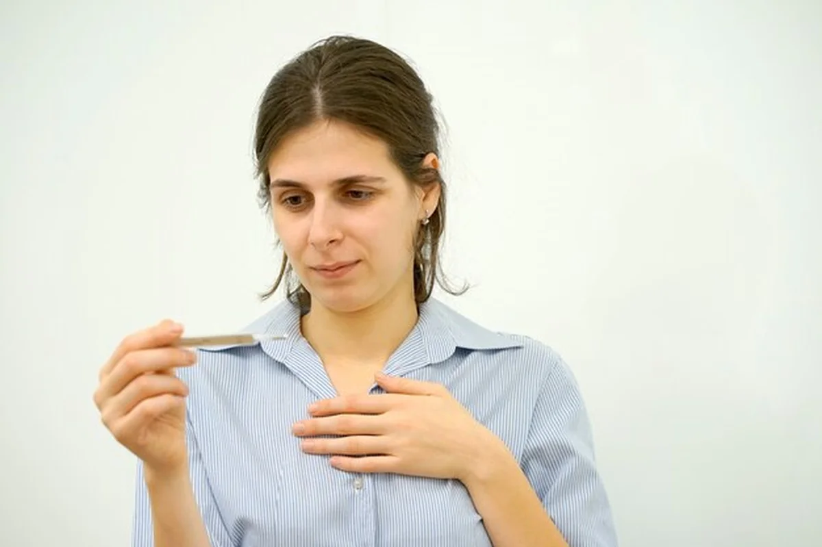 Chora kobieta mierząca temperaturę na kanapie