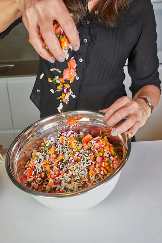 Osoba posypuje przyprawy na sałatkę w misce