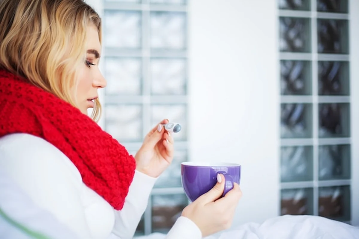 Chora kobieta w łóżku z termometrem ma wysoką gorączkę