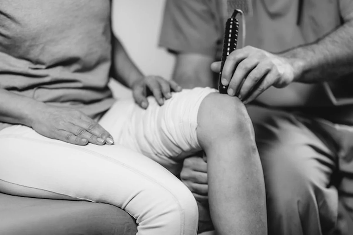 Fizjoterapeuta leczący kolano starszej kobiety