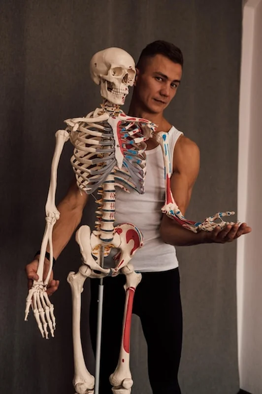 Mężczyzna trzyma kostkę nogi i wskazuje na nią palcem